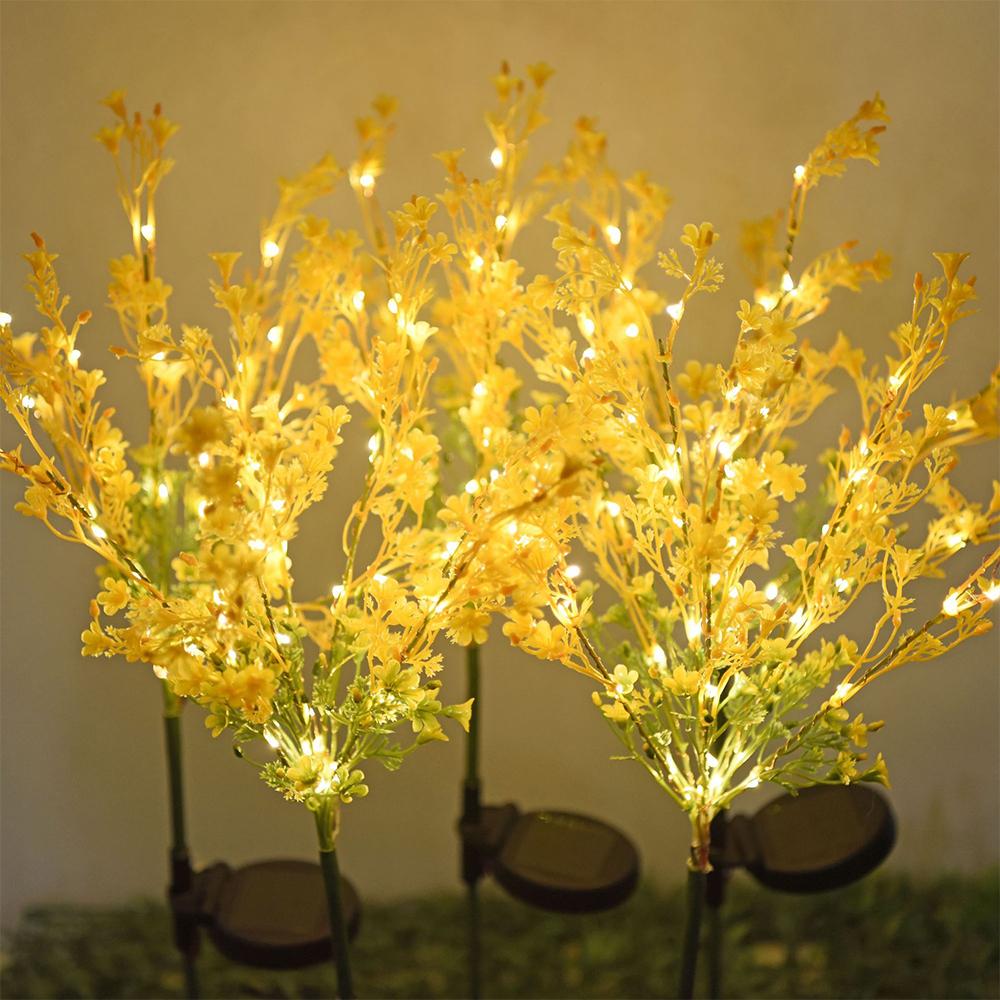 Two solar-powered canola flower shape lights glowing in a garden at night, showcasing their vibrant yellow color and realistic flower design.