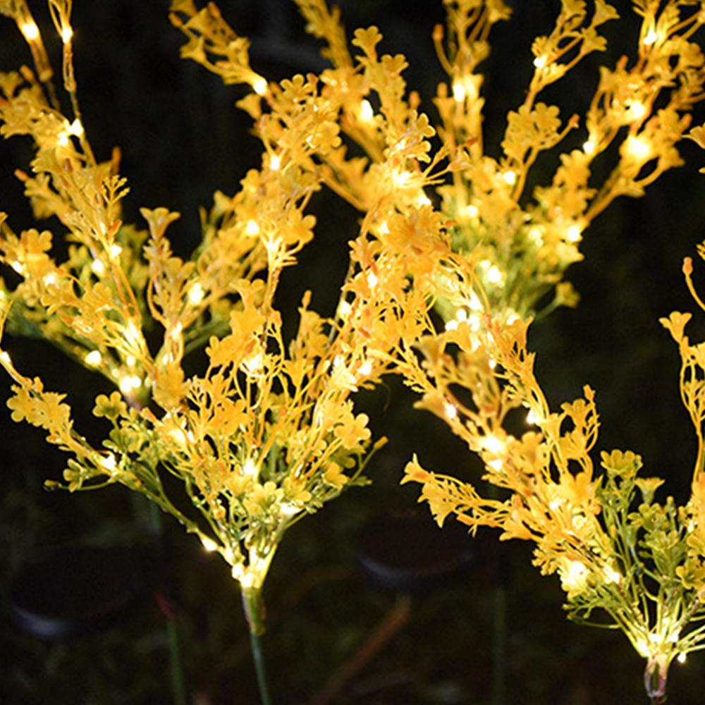 Two solar-powered canola flower shape lights glowing in a garden at night, showcasing their vibrant yellow color and realistic flower design.