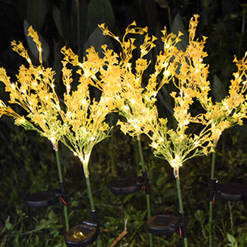 Two solar-powered canola flower shape lights glowing in a garden at night, showcasing their vibrant yellow color and realistic flower design.