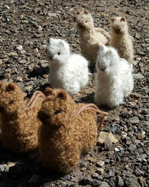 A collection of adorable hand made baby alpaca ornaments in various colors and sizes, showcasing their unique craftsmanship and charm.
