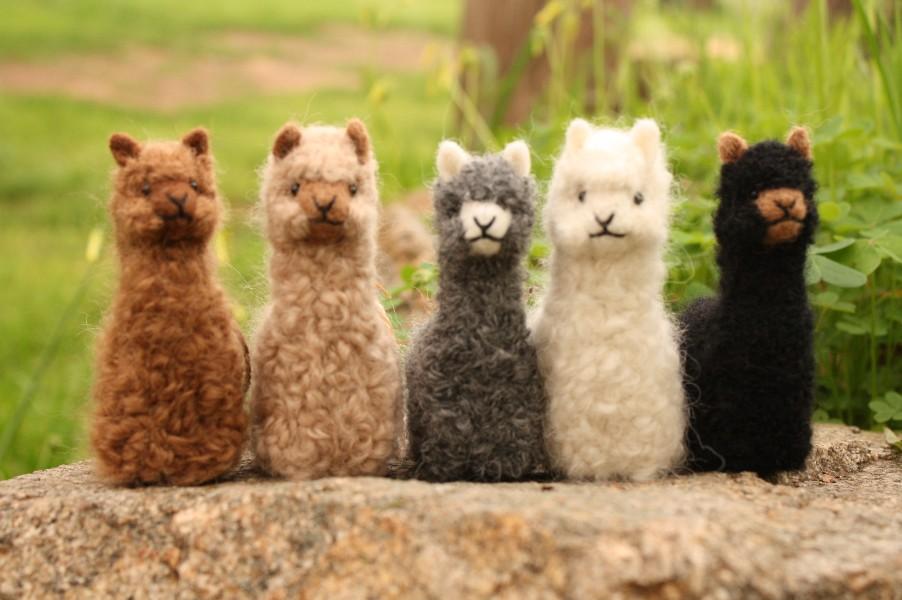 A collection of adorable hand made baby alpaca ornaments, showcasing their unique designs and soft textures, perfect for holiday decorations.