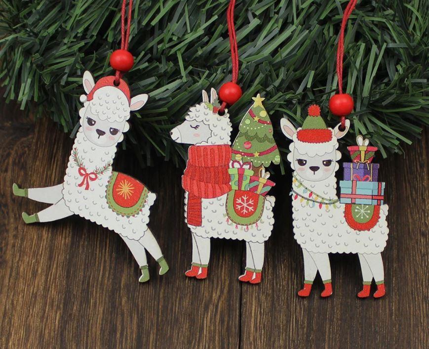A set of three painted wooden alpaca Christmas ornaments, featuring vibrant colors and red hanging strings, perfect for holiday decorations.