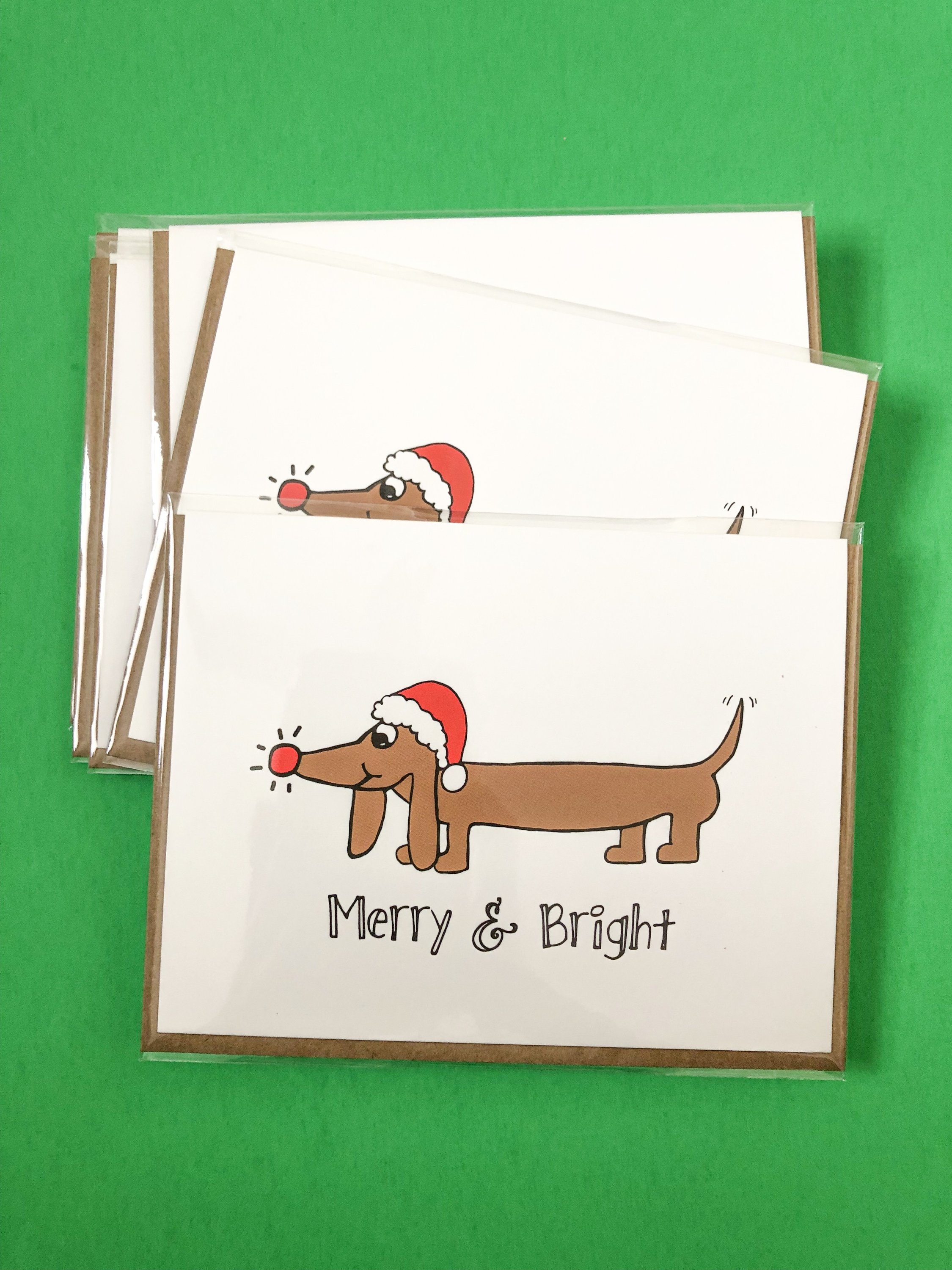 Dachshund Christmas Card featuring a dog in a Santa hat with festive text.