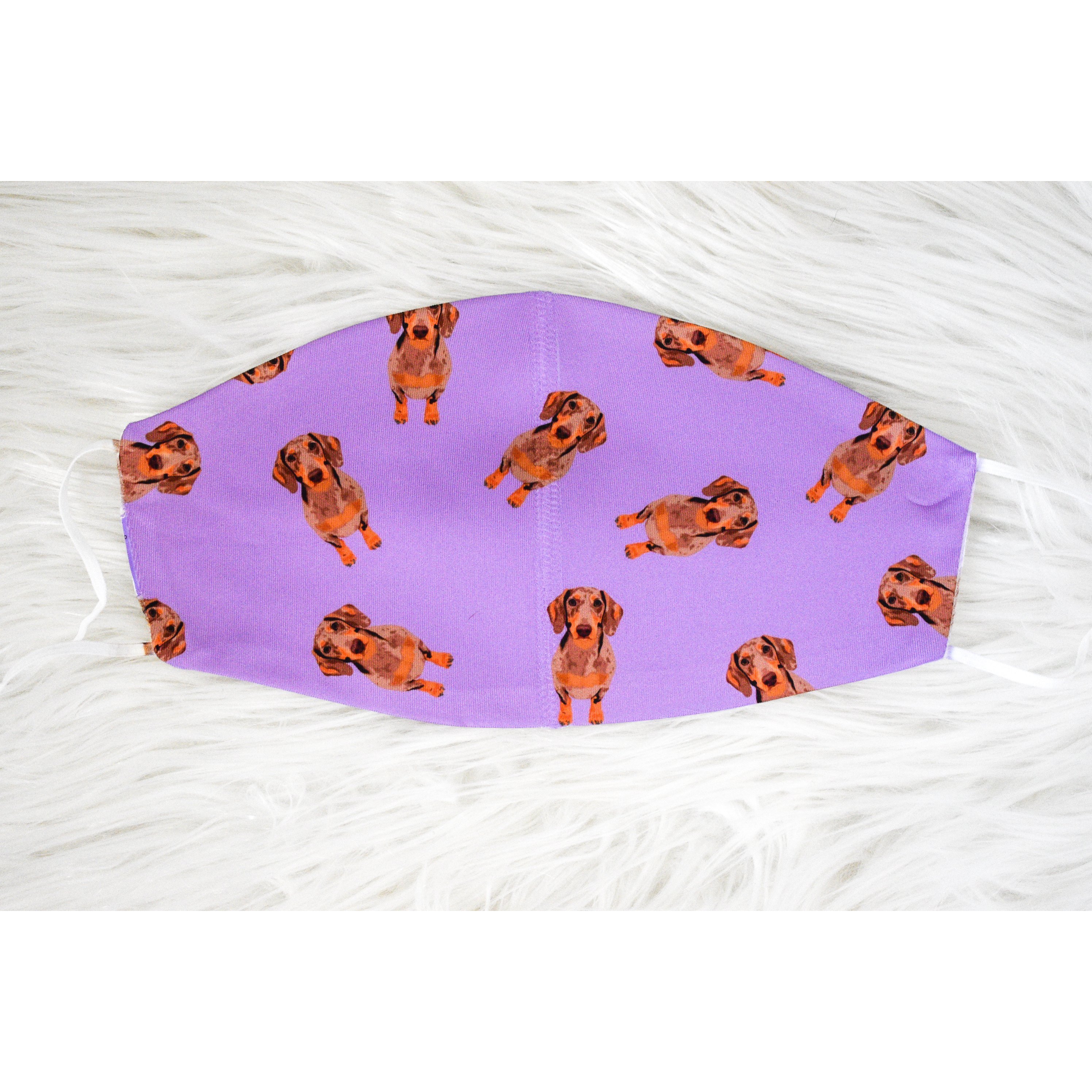 A handmade Dachshund face covering featuring a cute dachshund print, made from breathable polyester and organic cotton, suitable for adults.