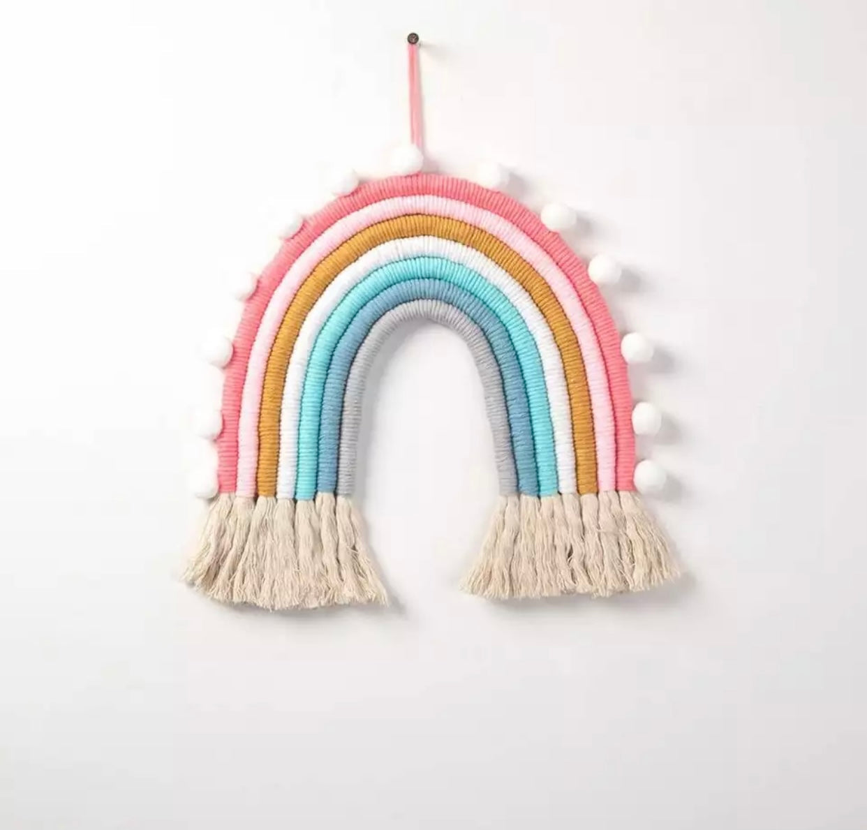 A colorful handmade rope rainbow wall hanging, featuring vibrant hues and a chunky design, perfect for nursery decor.