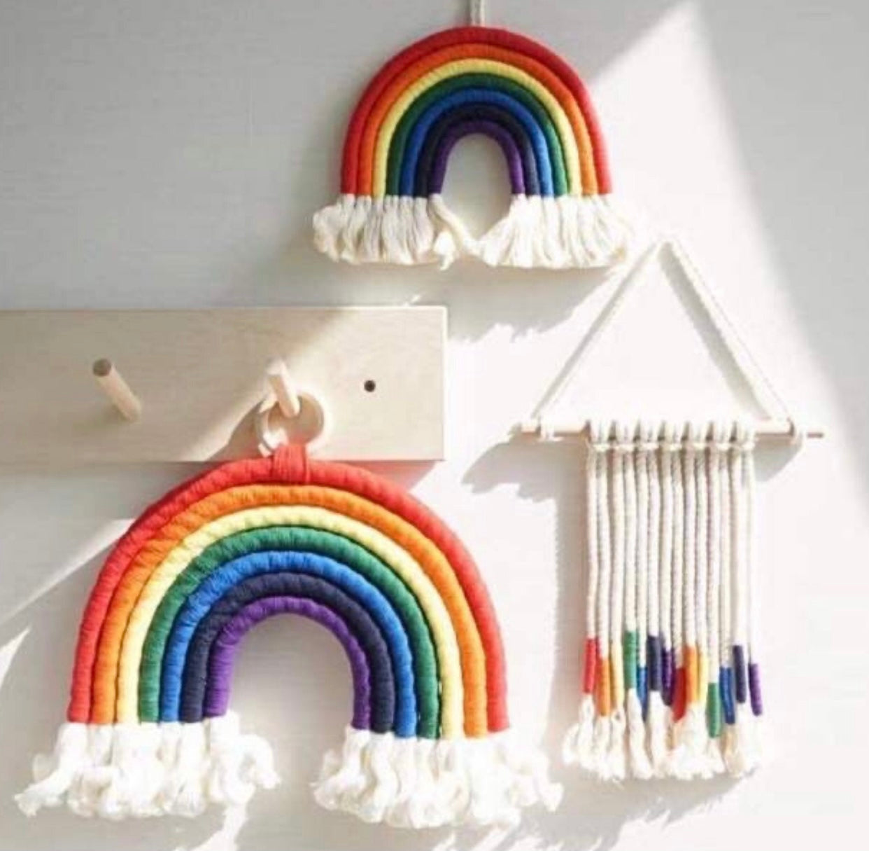 A colorful handmade rope rainbow wall hanging, featuring vibrant hues and a chunky design, perfect for nursery decor.