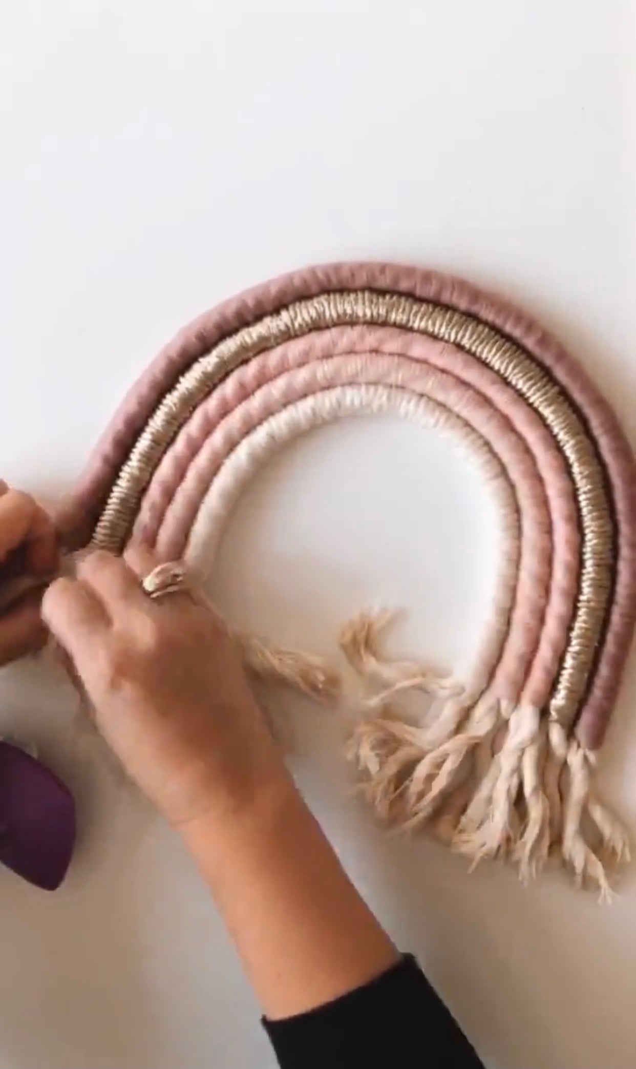 A colorful handmade rope rainbow wall hanging, featuring vibrant hues and a chunky design, perfect for nursery decor.