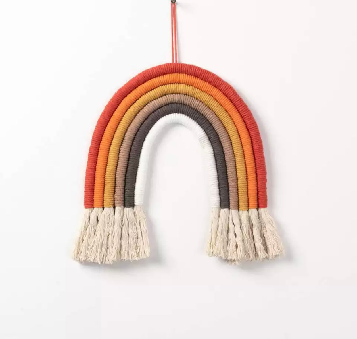 A colorful handmade rope rainbow wall hanging, featuring vibrant hues and a chunky design, perfect for nursery decor.