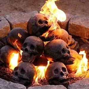 Ceramic Halloween fire pit skull with hollow eye sockets, flames dancing through its eyes, creating a spooky atmosphere.