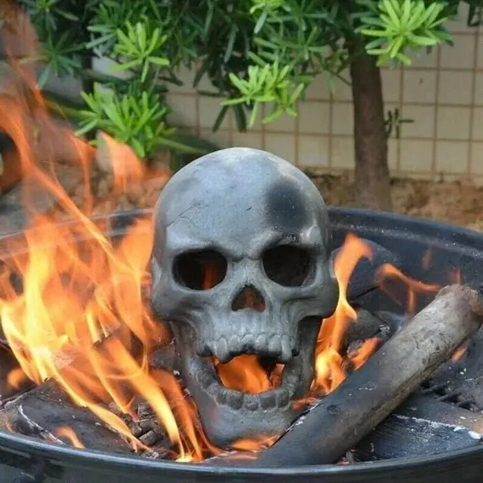 Ceramic Halloween fire pit skull with hollow eye sockets, flames dancing through its eyes, creating a spooky atmosphere.