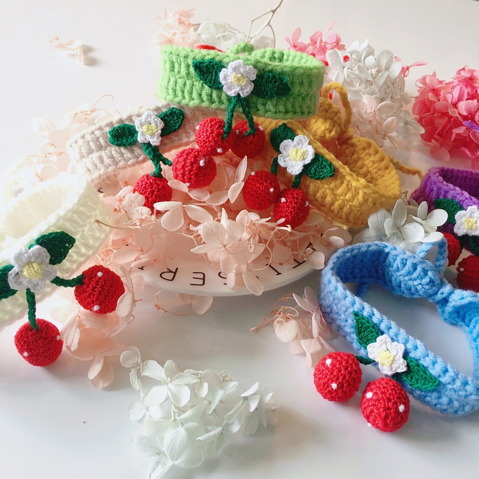 A collection of handmade cherry accessories for pets, featuring vibrant colors and unique designs.