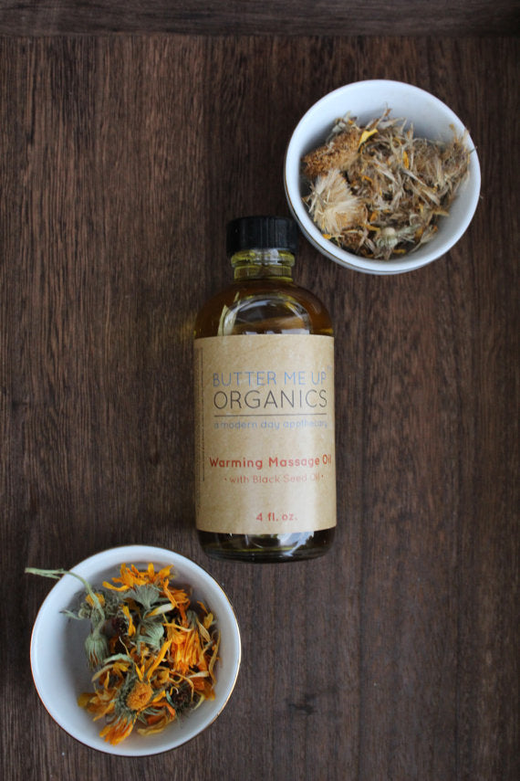 A 4oz glass bottle of Organic Warming Massage Oil with a soothing blend of natural ingredients for muscle relief.