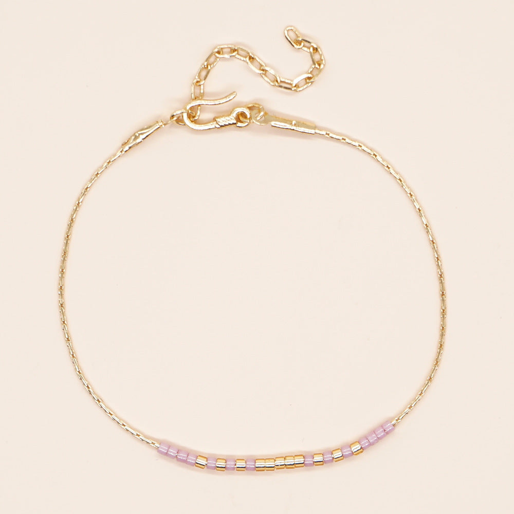Delicate gold double-strand bracelet with colorful beads, showcasing minimalist design and lobster claw closure.