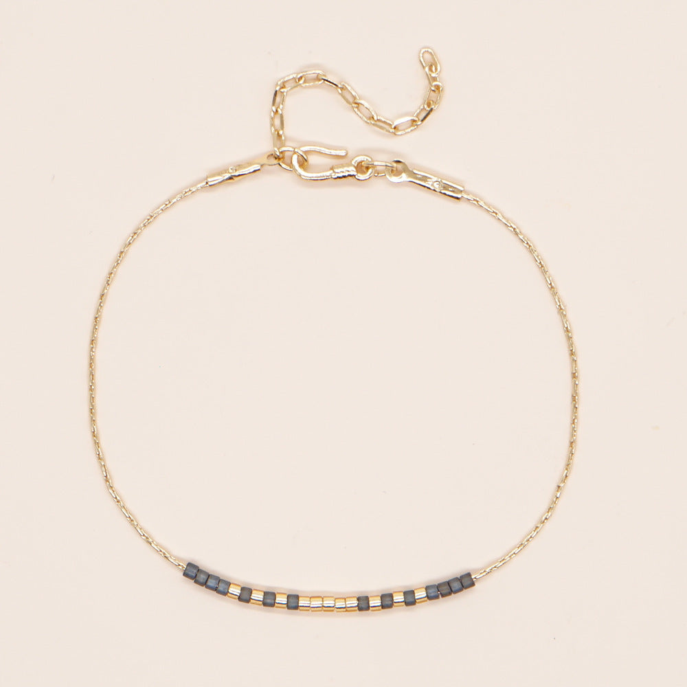 Delicate gold double-strand bracelet with colorful beads, showcasing minimalist style and elegant craftsmanship.