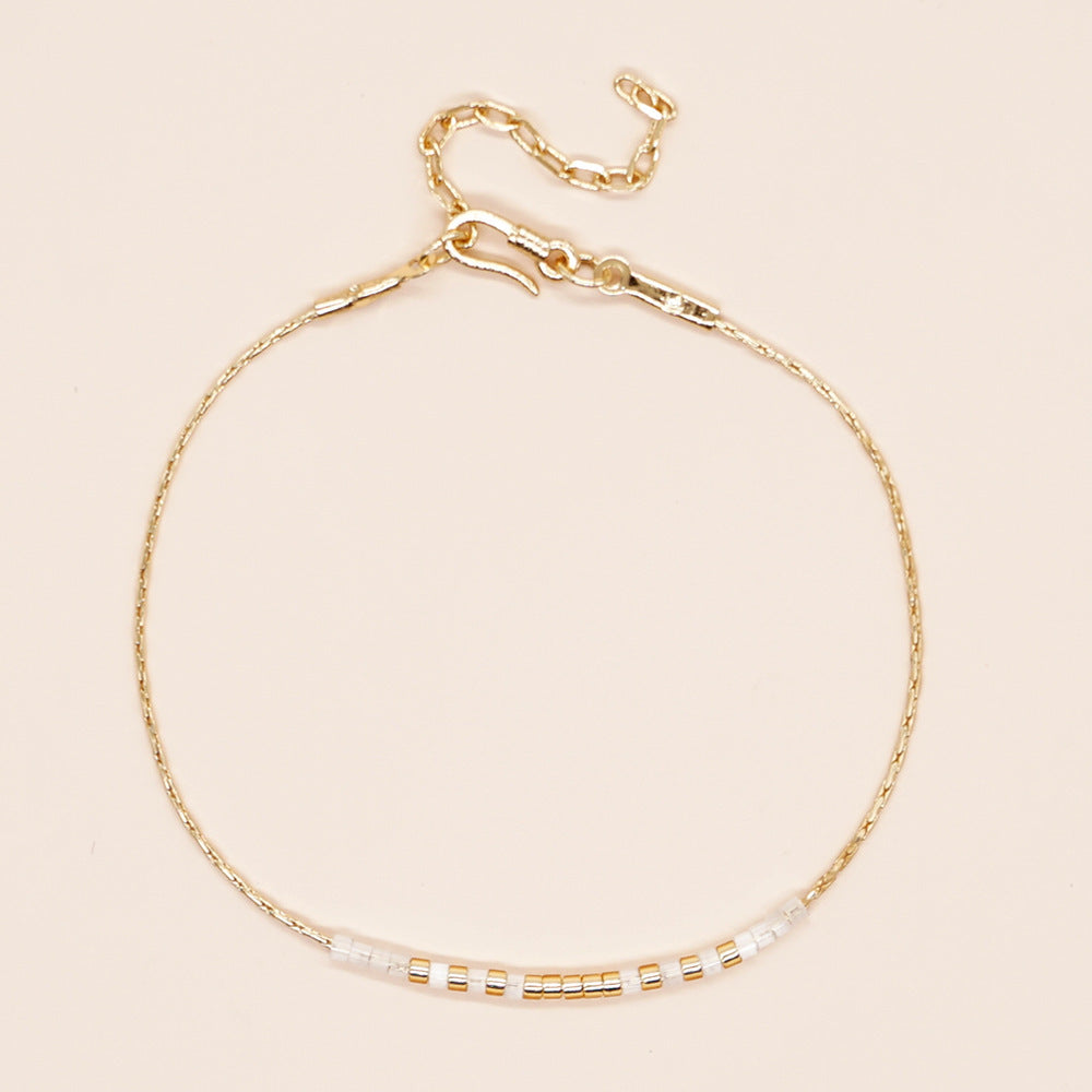 Delicate gold double-strand bracelet with colorful beads, featuring a lobster claw closure.