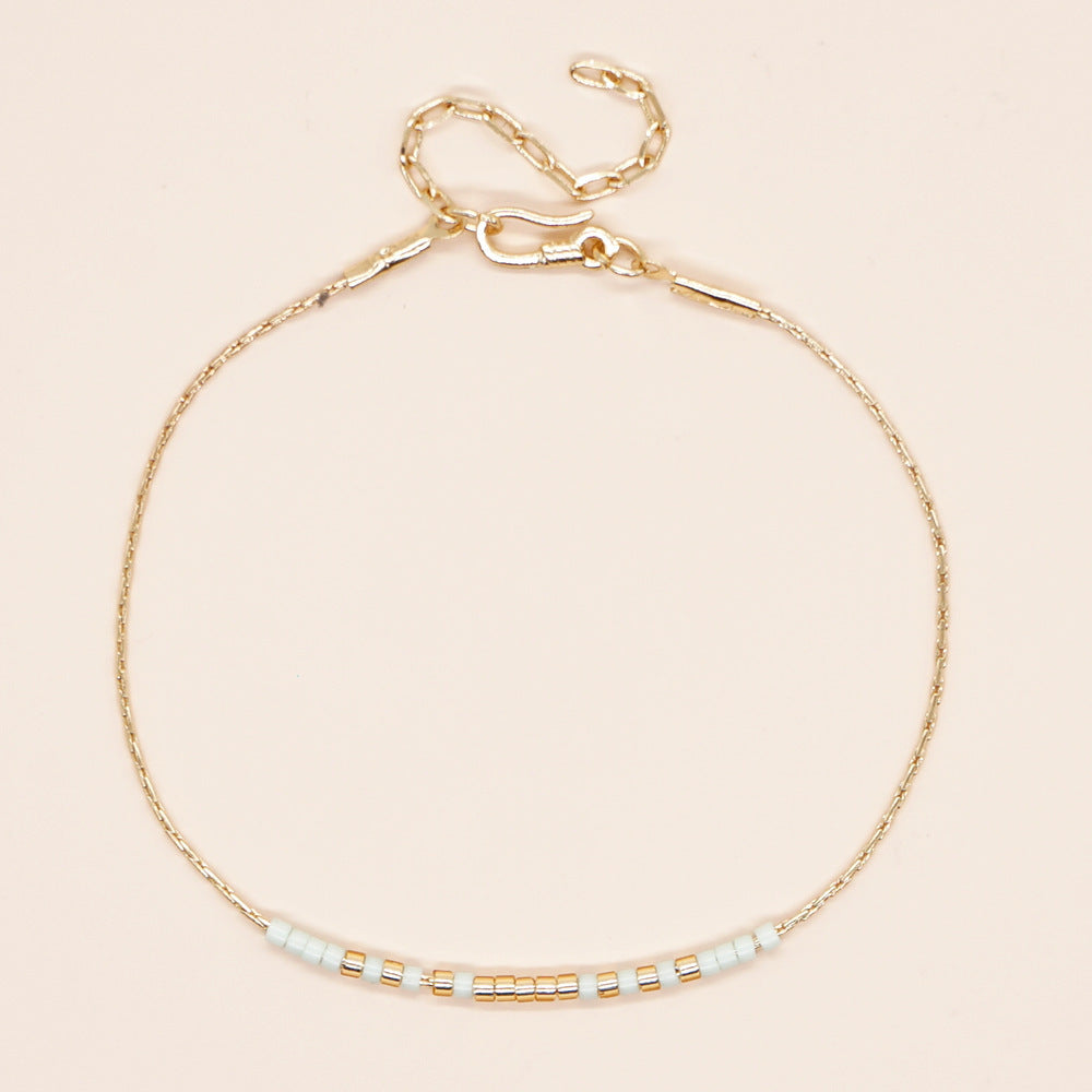 Delicate gold double-strand bracelet with colorful beads, featuring a lobster claw closure.