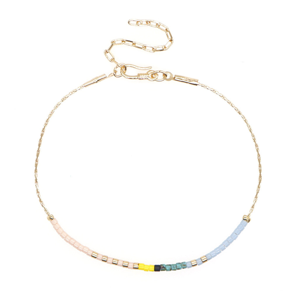 Delicate gold double-strand bracelet with colorful beaded accents, featuring a lobster claw closure.