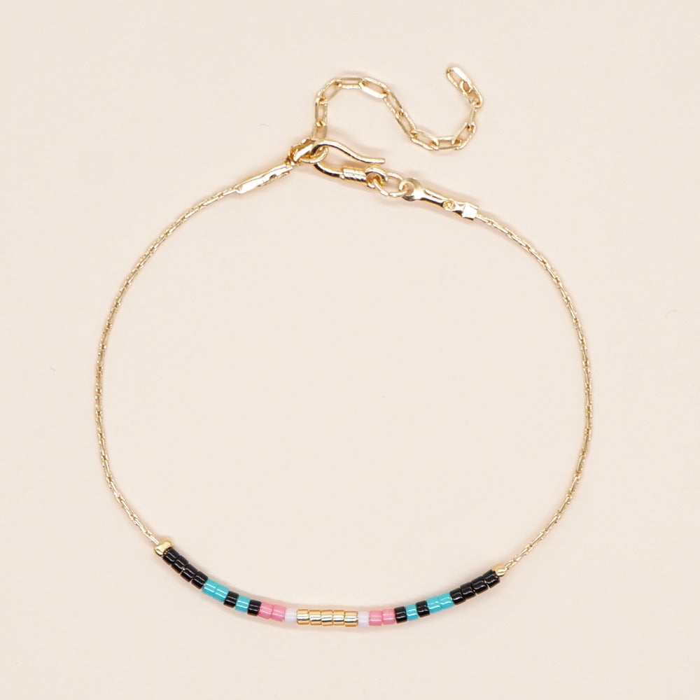 Delicate gold double-strand bracelet with colorful beads, featuring a lobster claw closure.
