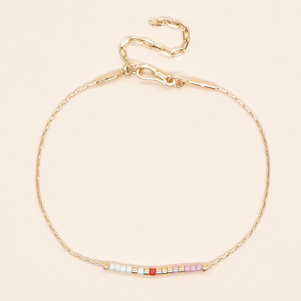 Delicate gold double-strand bracelet with colorful beads, featuring a lobster claw closure.