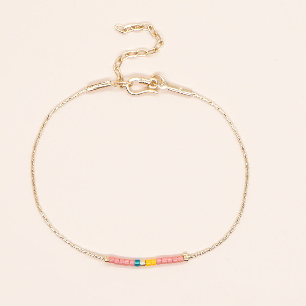 Delicate gold double-strand bracelet with colorful beads, featuring a lobster claw closure.