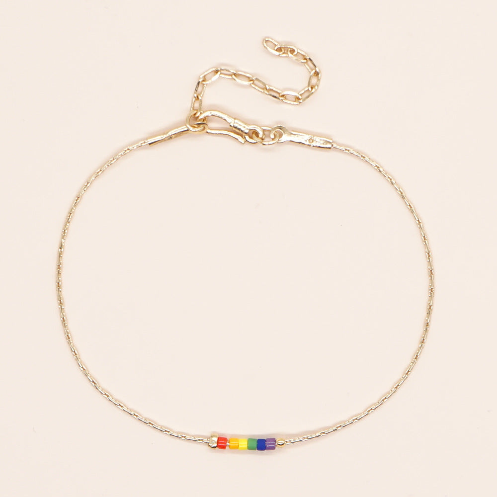 Delicate gold double-strand bracelet with colorful beads, featuring a lobster claw closure.