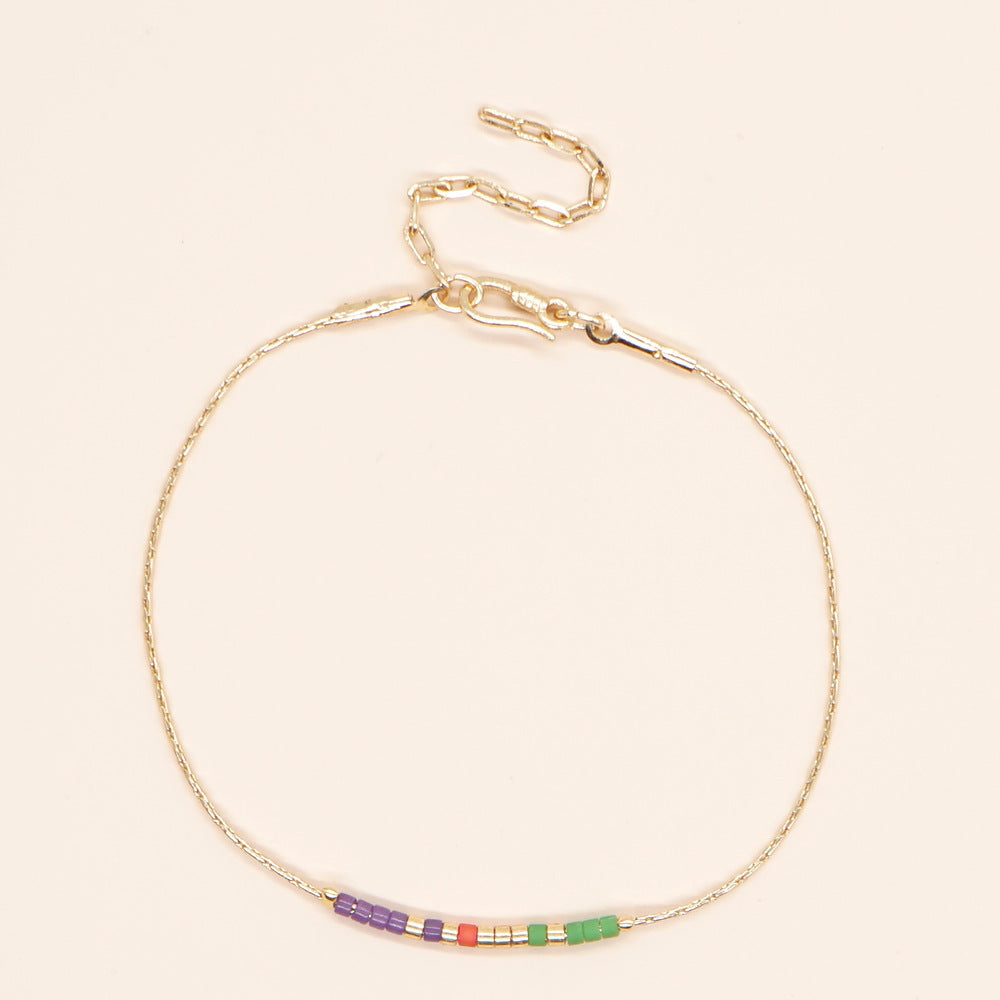 Delicate gold double-strand bracelet with colorful beads, featuring a lobster claw closure.