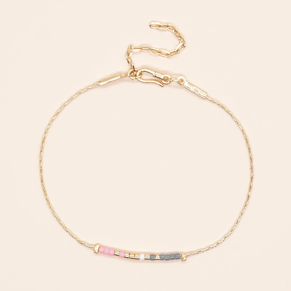 Delicate gold double-strand bracelet with colorful beads, featuring a lobster claw closure, made of 18k gold-plated brass.