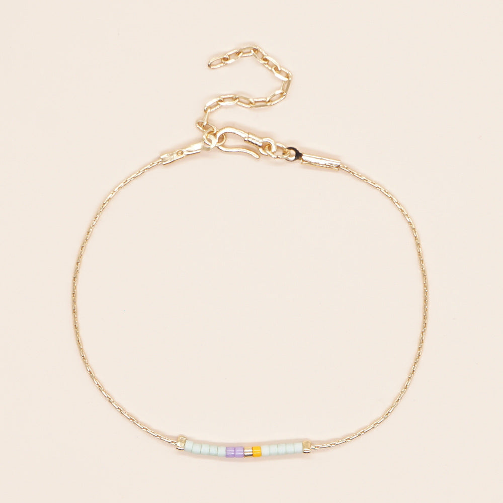 Delicate gold double-strand bracelet with colorful beads, featuring a lobster claw closure.