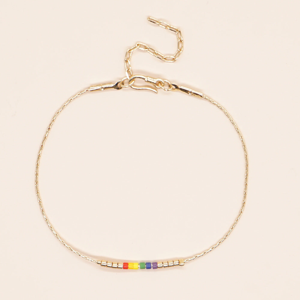 Delicate gold double-strand bracelet with colorful beads, featuring a lobster claw closure.
