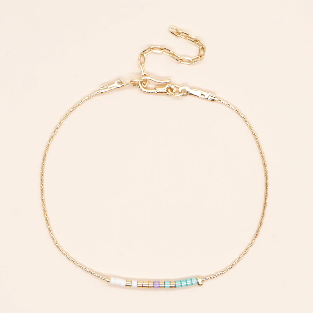 Delicate gold double-strand bracelet with colorful beads, featuring a lobster claw closure, perfect for minimalist style.