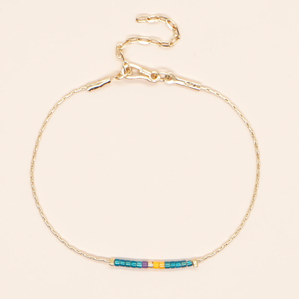 Delicate gold double-strand bracelet with colorful beads, featuring a lobster claw closure.