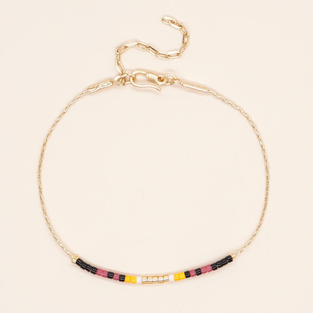 Delicate gold double-strand bracelet with colorful beads, featuring a lobster claw closure, showcasing minimalist style.