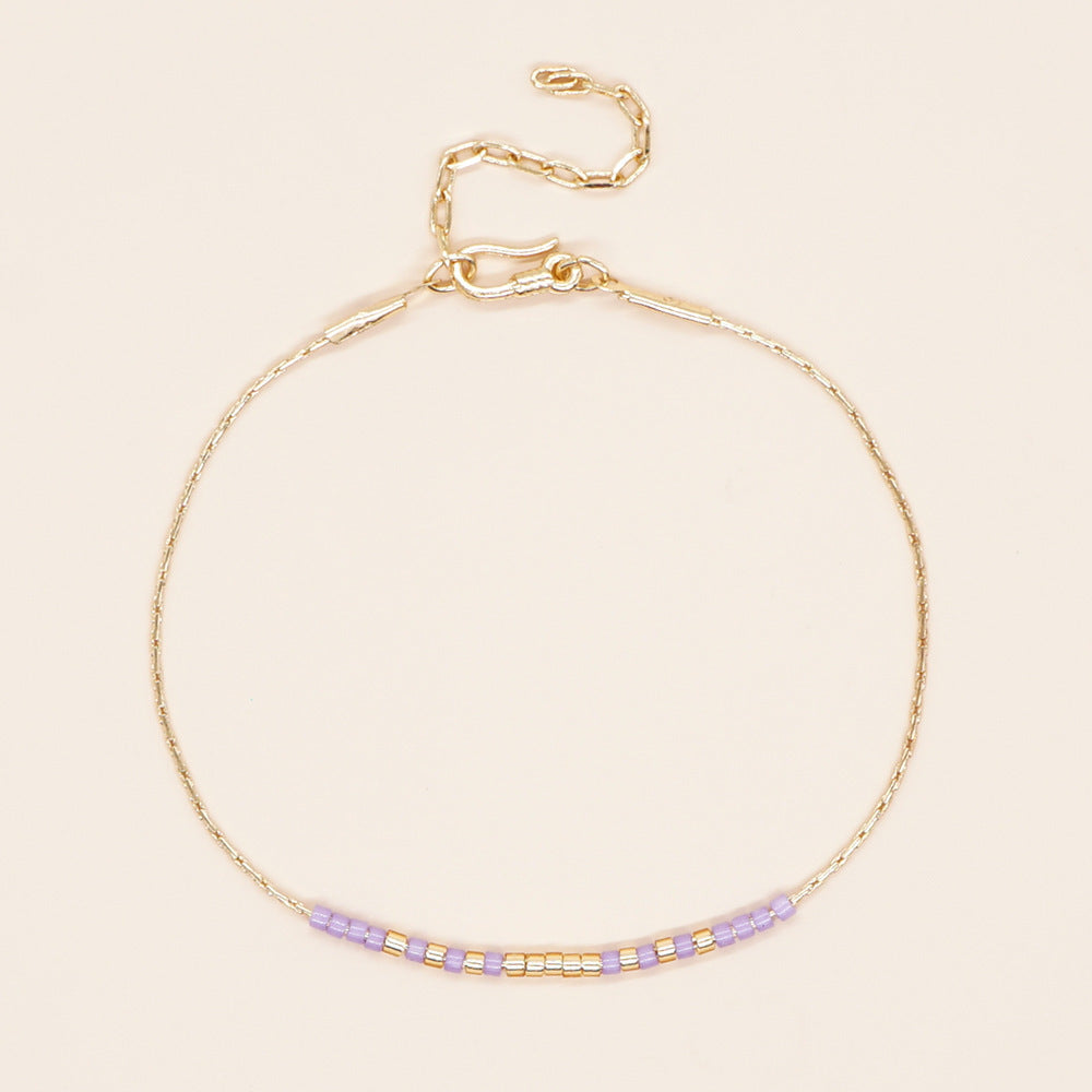 Delicate gold double-strand bracelet with colorful beaded accents, featuring a lobster claw closure.