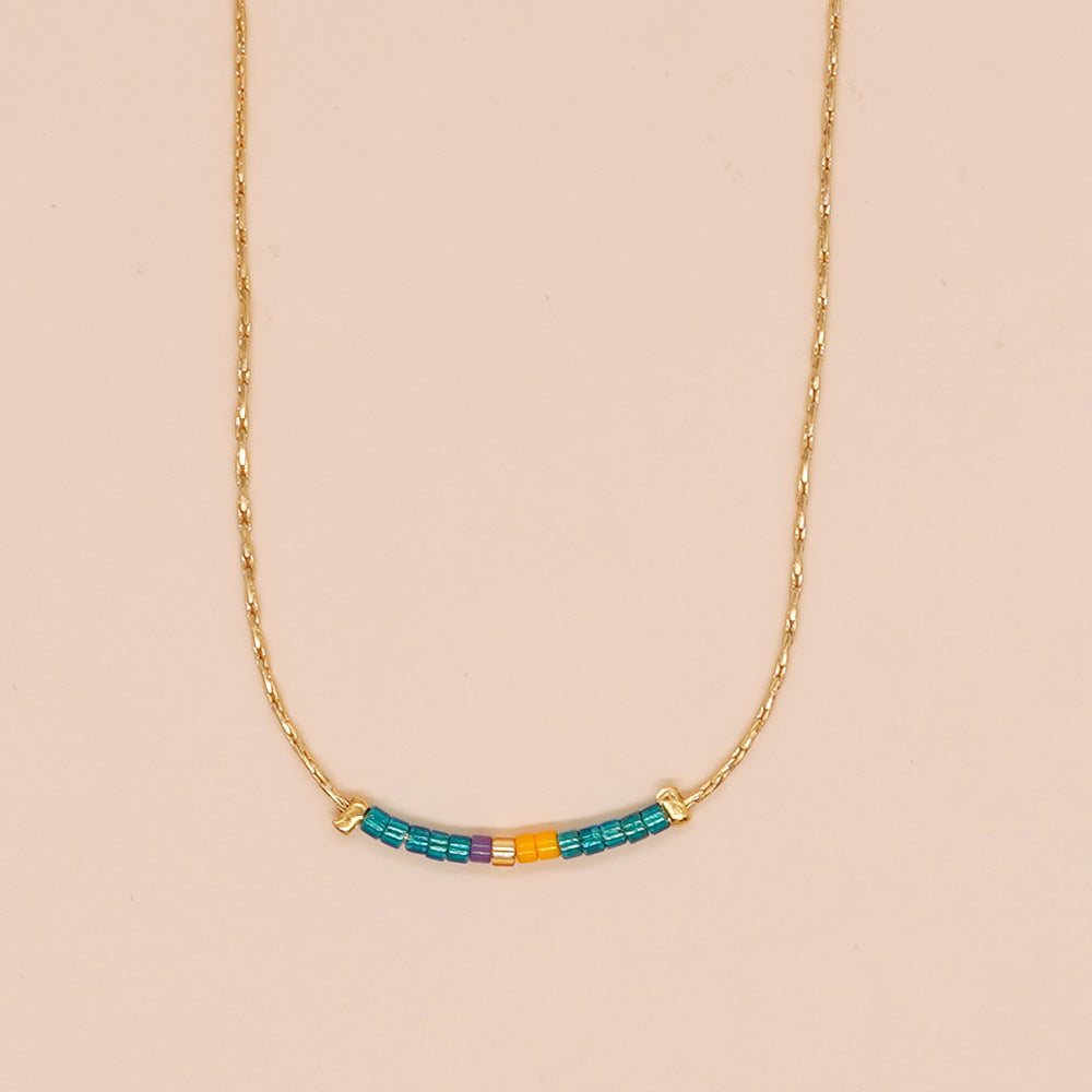 Delicate gold double-strand necklace with colorful beaded accents, featuring a lobster claw closure, perfect for minimalist style.