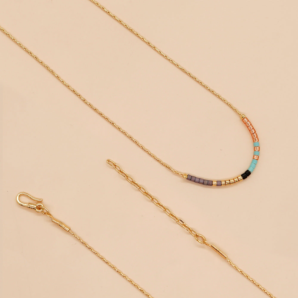 Delicate gold double-strand necklace with colorful beaded accents, featuring a lobster claw closure.