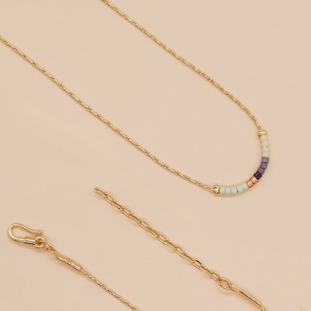Delicate gold double-strand necklace with colorful beaded accents, featuring a lobster claw closure, perfect for minimalist style.