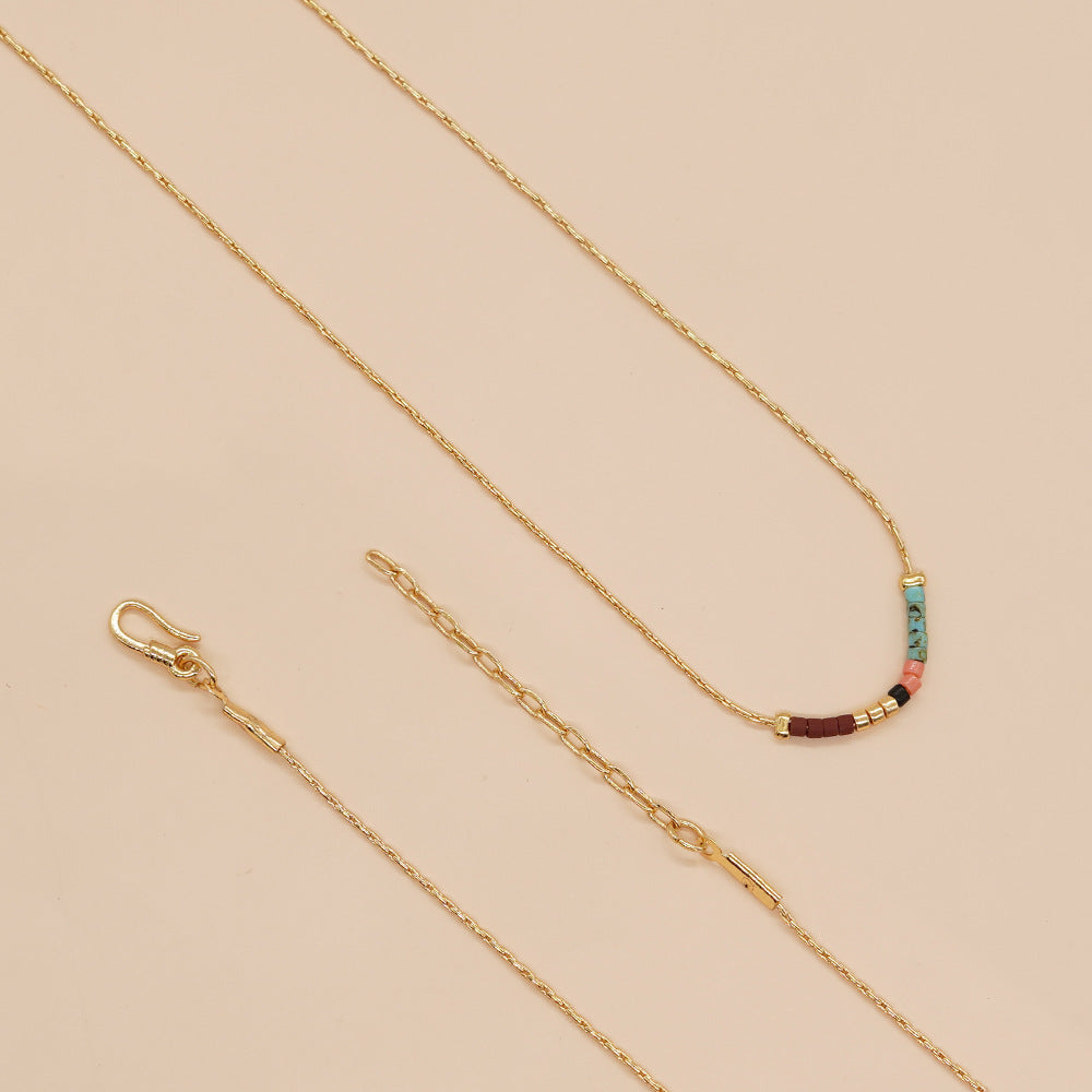 Delicate gold double-strand necklace with colorful beaded accents, featuring a lobster claw closure.