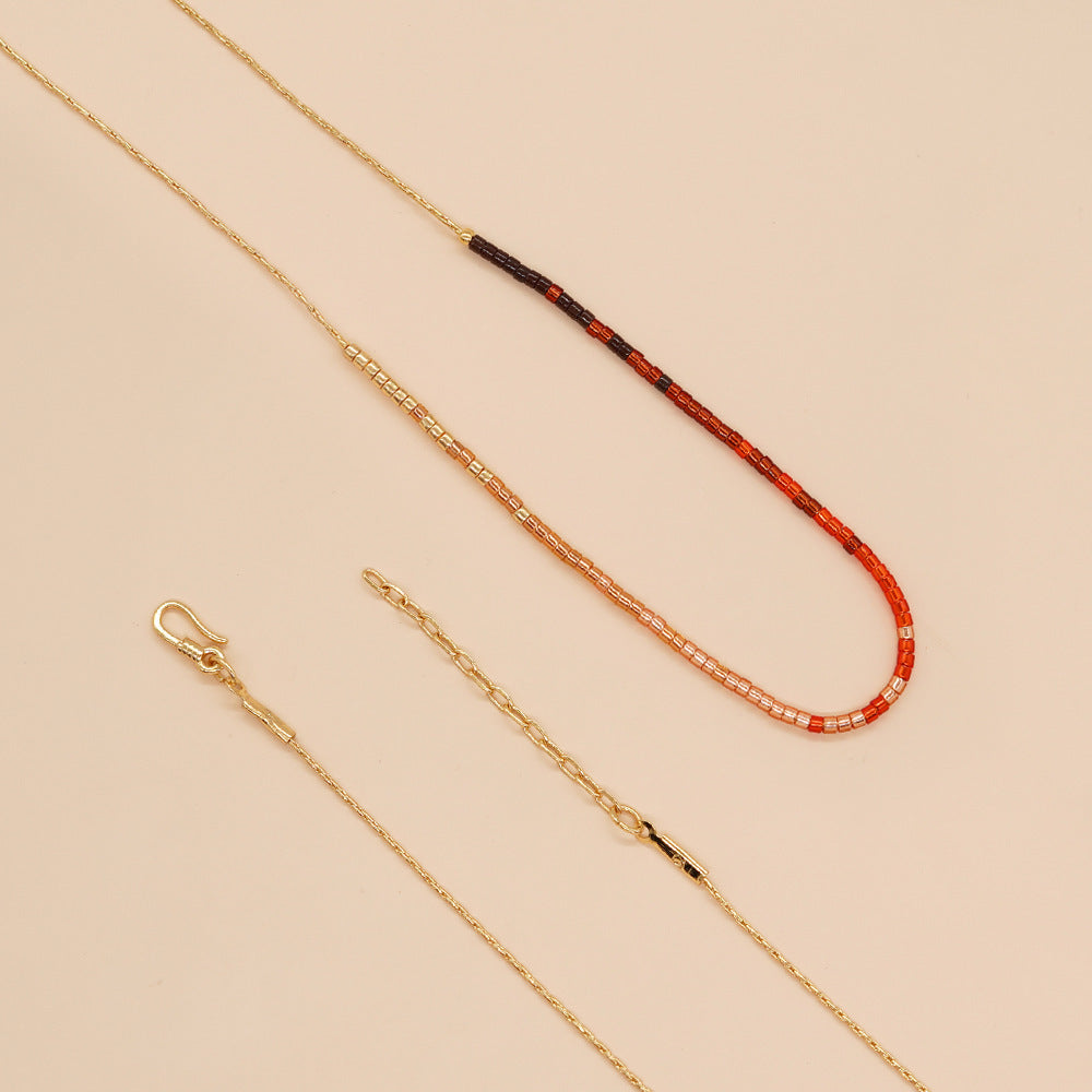 Delicate gold double-strand necklace with colorful beaded accents, featuring a lobster claw closure, perfect for minimalist style.