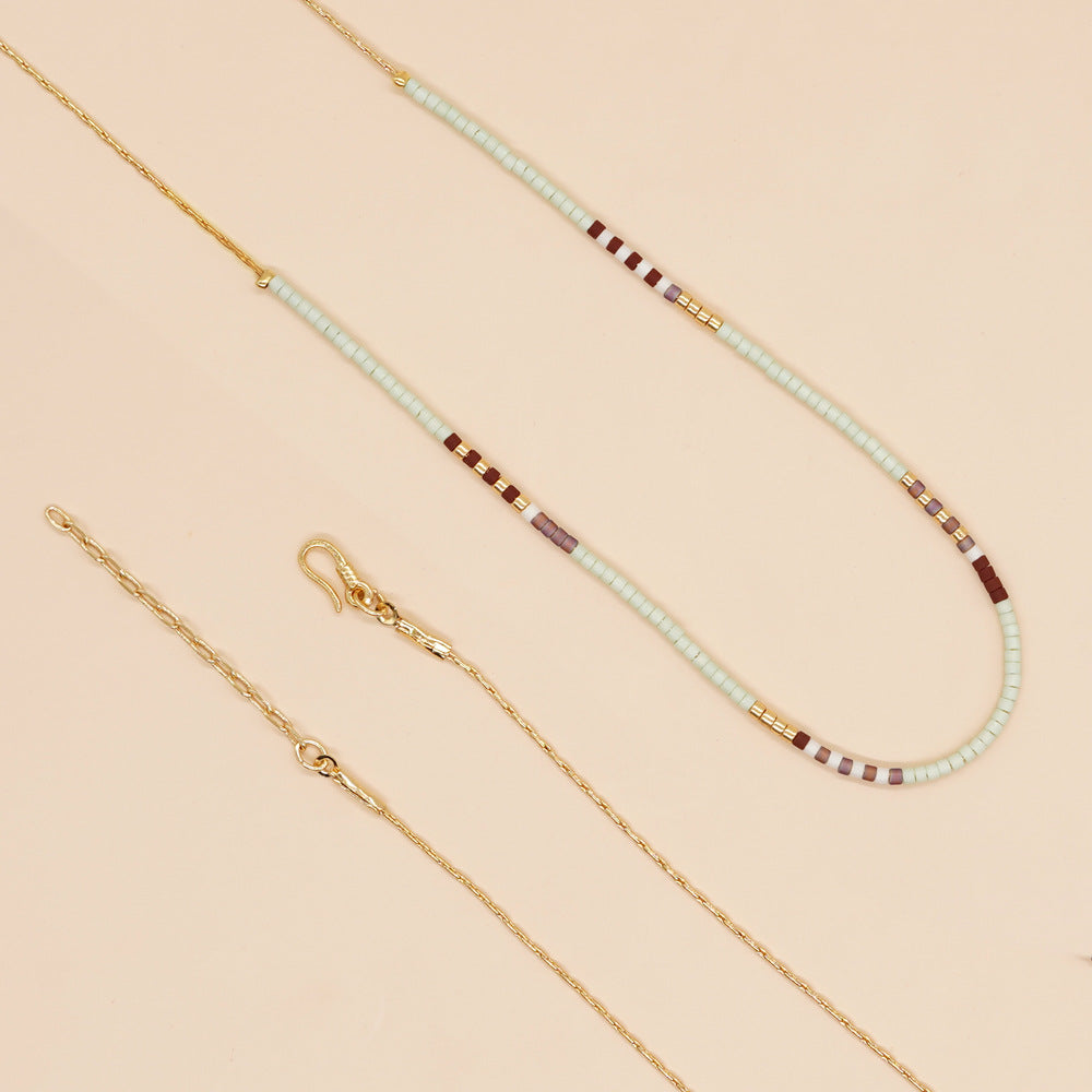 Delicate gold double-strand necklace with colorful beaded accents, featuring a lobster claw closure.