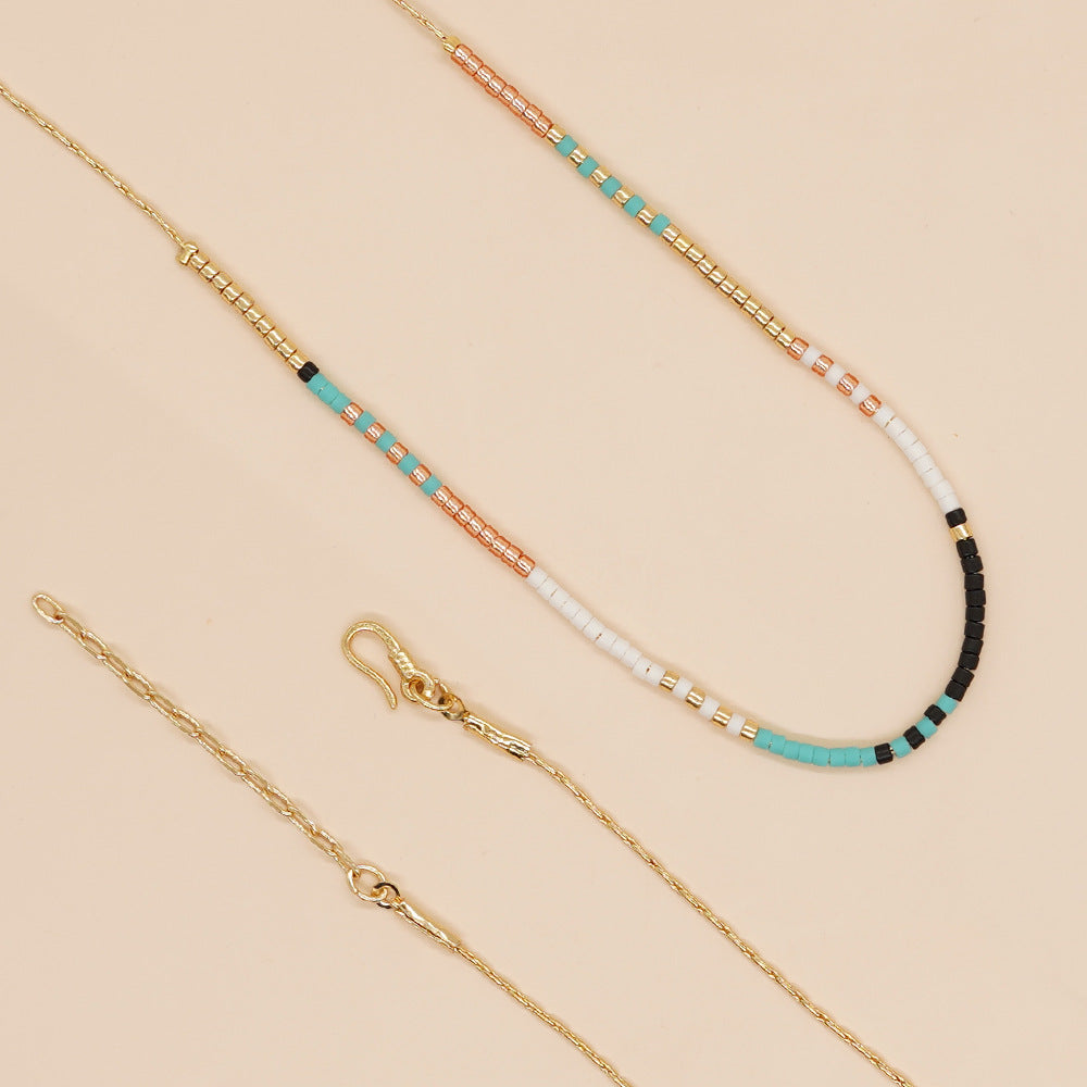 Delicate gold double-strand necklace with colorful beaded accents, featuring a lobster claw closure, perfect for minimalist style.