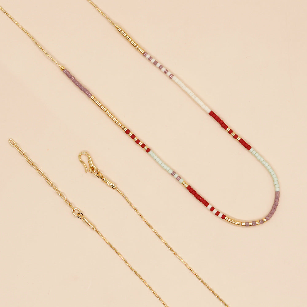 Delicate gold double-strand necklace with colorful beaded accents, featuring a lobster claw closure, perfect for minimalist style.