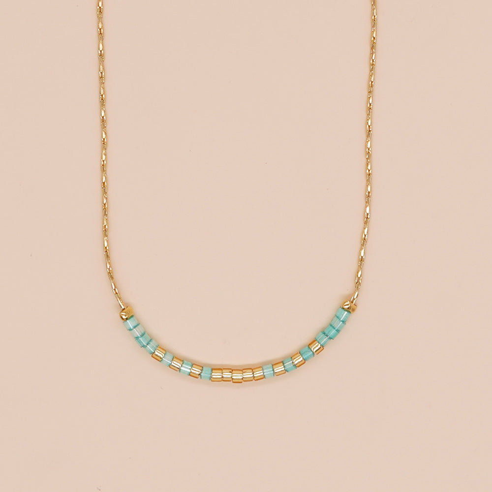 Delicate gold double-strand necklace with colorful beaded accents, featuring a lobster claw closure.