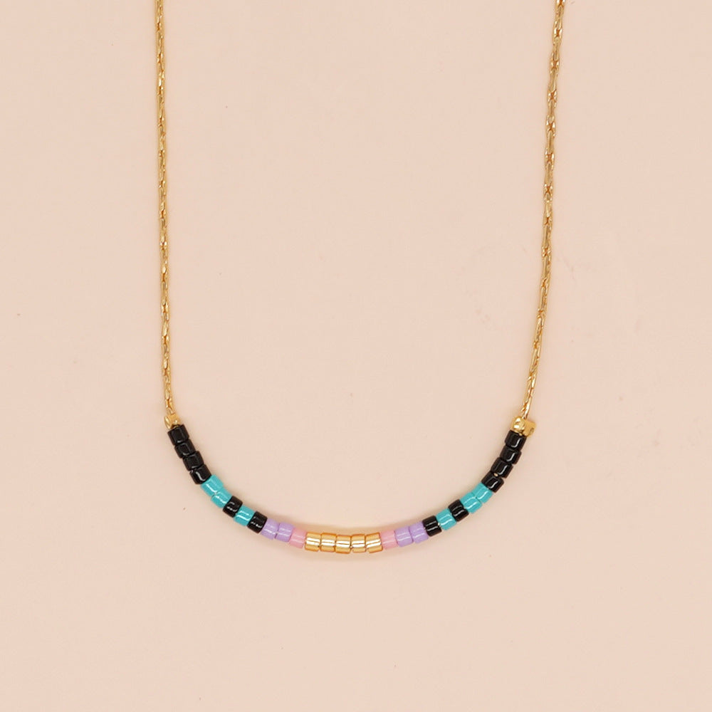 Delicate gold double-strand necklace with colorful beaded accents, featuring a lobster claw closure, perfect for minimalist style.