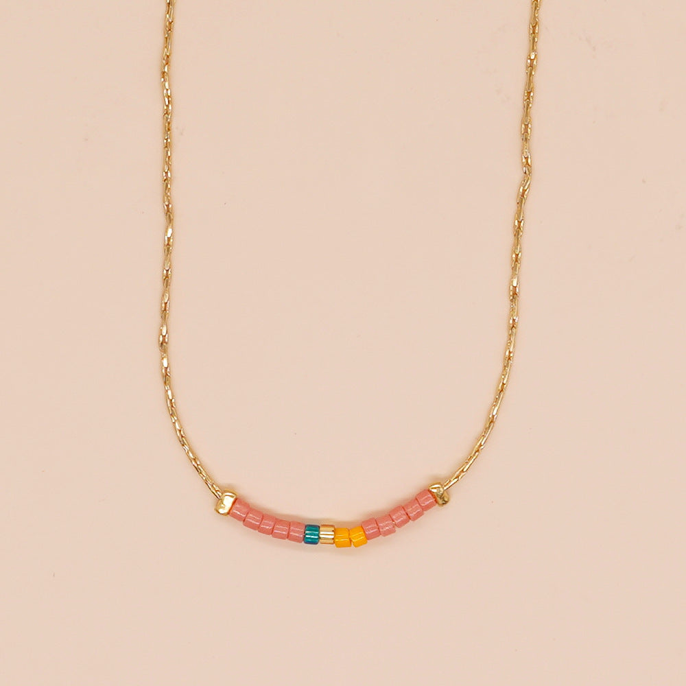 Delicate gold double-strand necklace with colorful beaded accents, featuring a lobster claw closure, perfect for minimalist style.