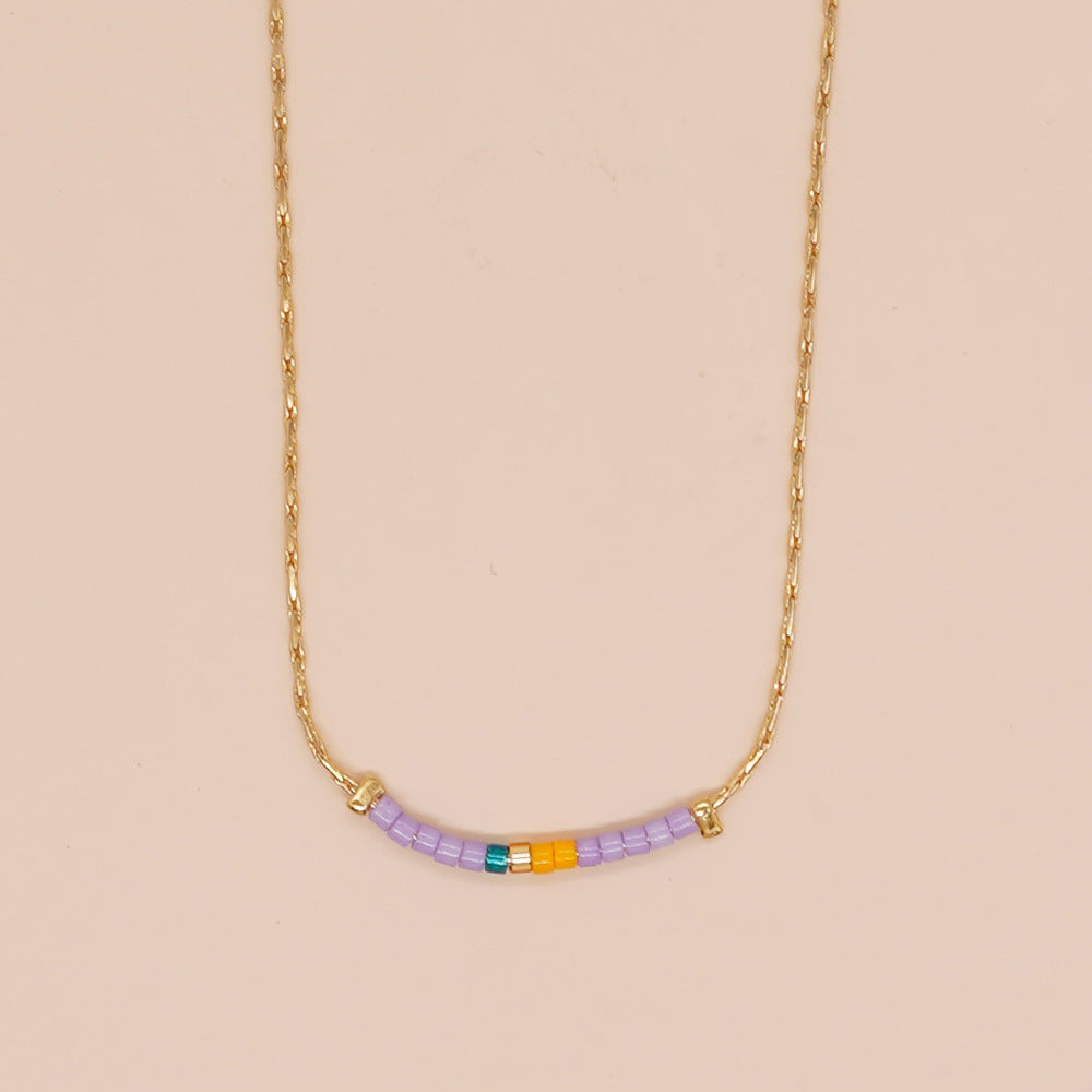 Delicate gold double-strand necklace with colorful beaded accents, featuring a lobster claw closure.