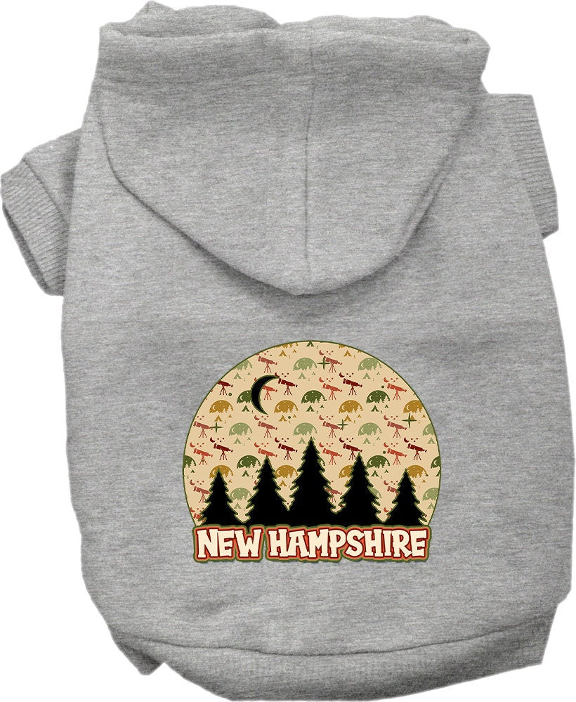 A small to medium pet wearing a cozy screen printed hoodie with a 'New Hampshire Under The Stars' design, showcasing its soft fabric and convenient leash access.
