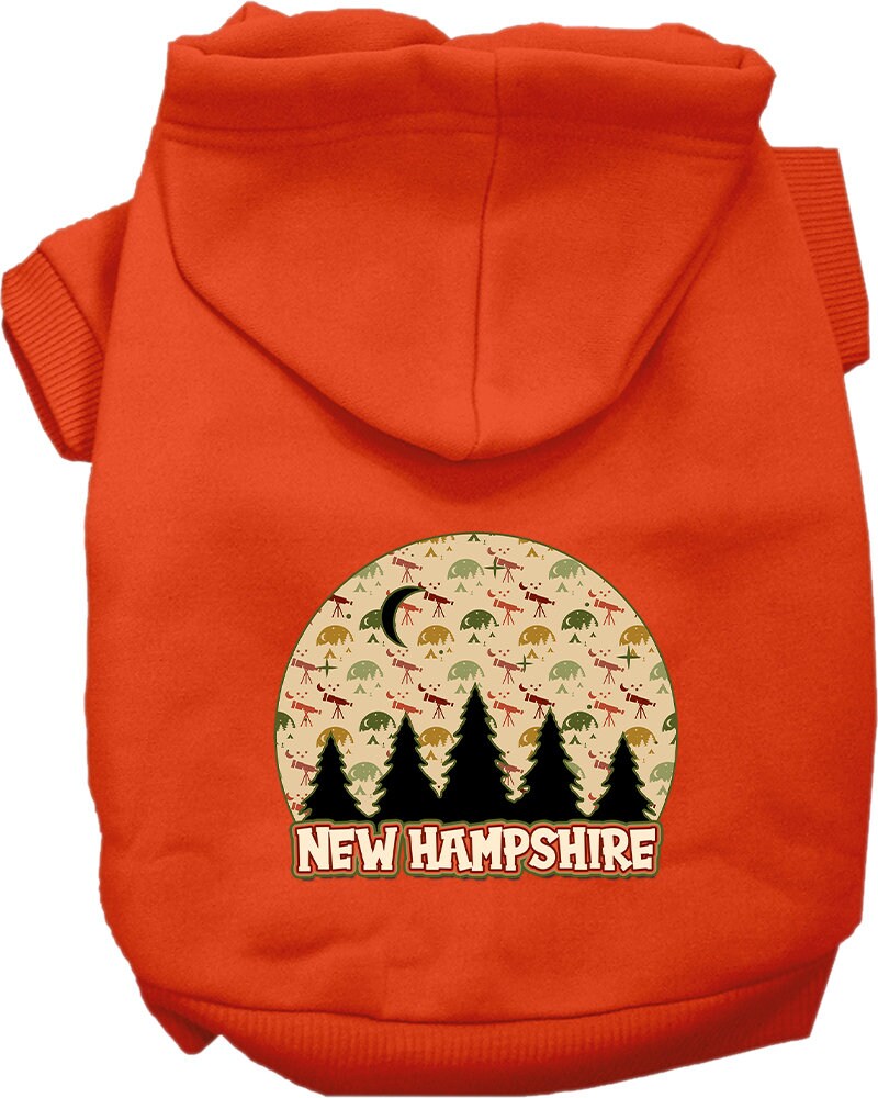 A small to medium pet wearing a cozy screen printed hoodie with a 'New Hampshire Under The Stars' design, showcasing its soft fabric and convenient leash access.