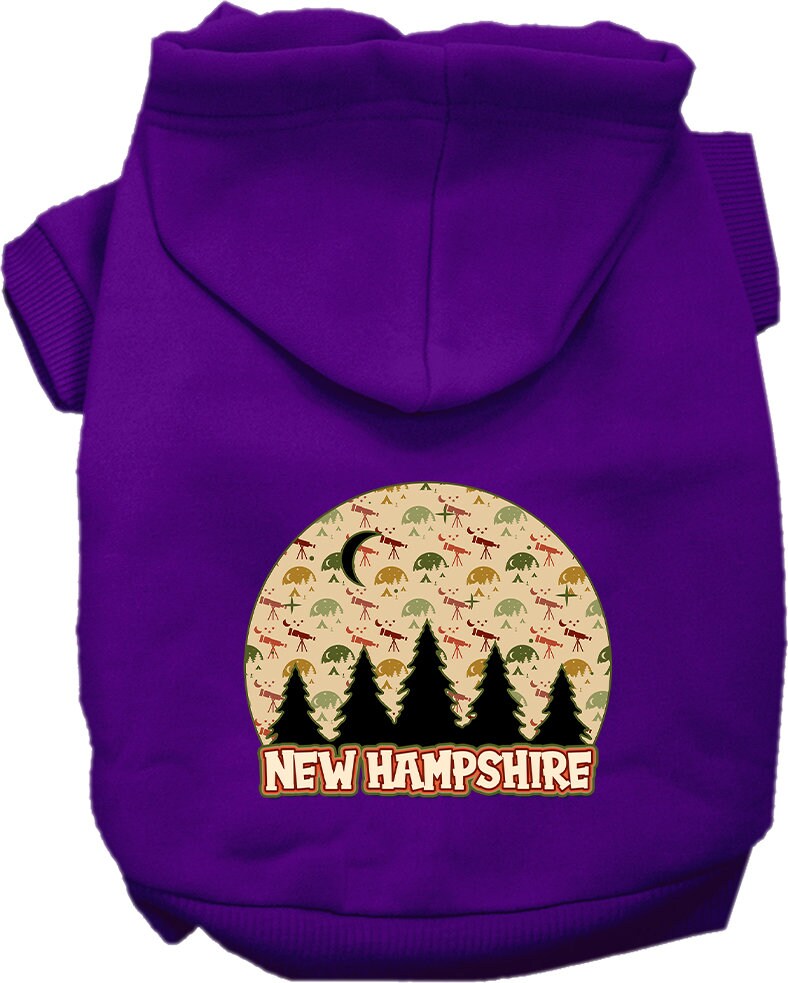 A small to medium pet wearing a cozy screen printed hoodie with a 'New Hampshire Under The Stars' design, showcasing its soft fabric and convenient leash access.