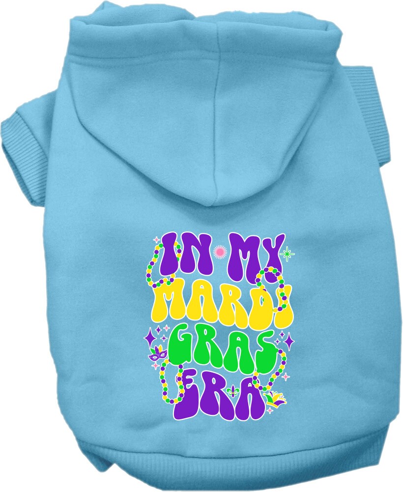 A small to medium pet wearing a colorful screen printed hoodie with the text 'In My Mardi Gras Era', showcasing a festive design.