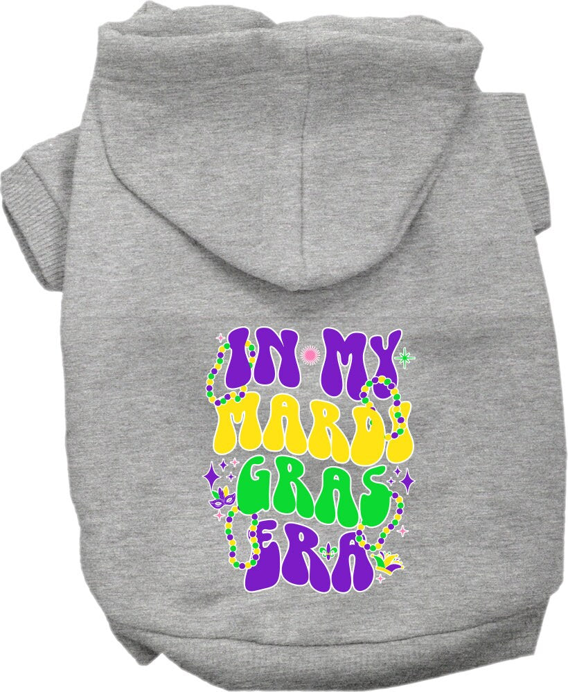A small to medium pet wearing a colorful screen printed hoodie with the text 'In My Mardi Gras Era', showcasing a festive design.